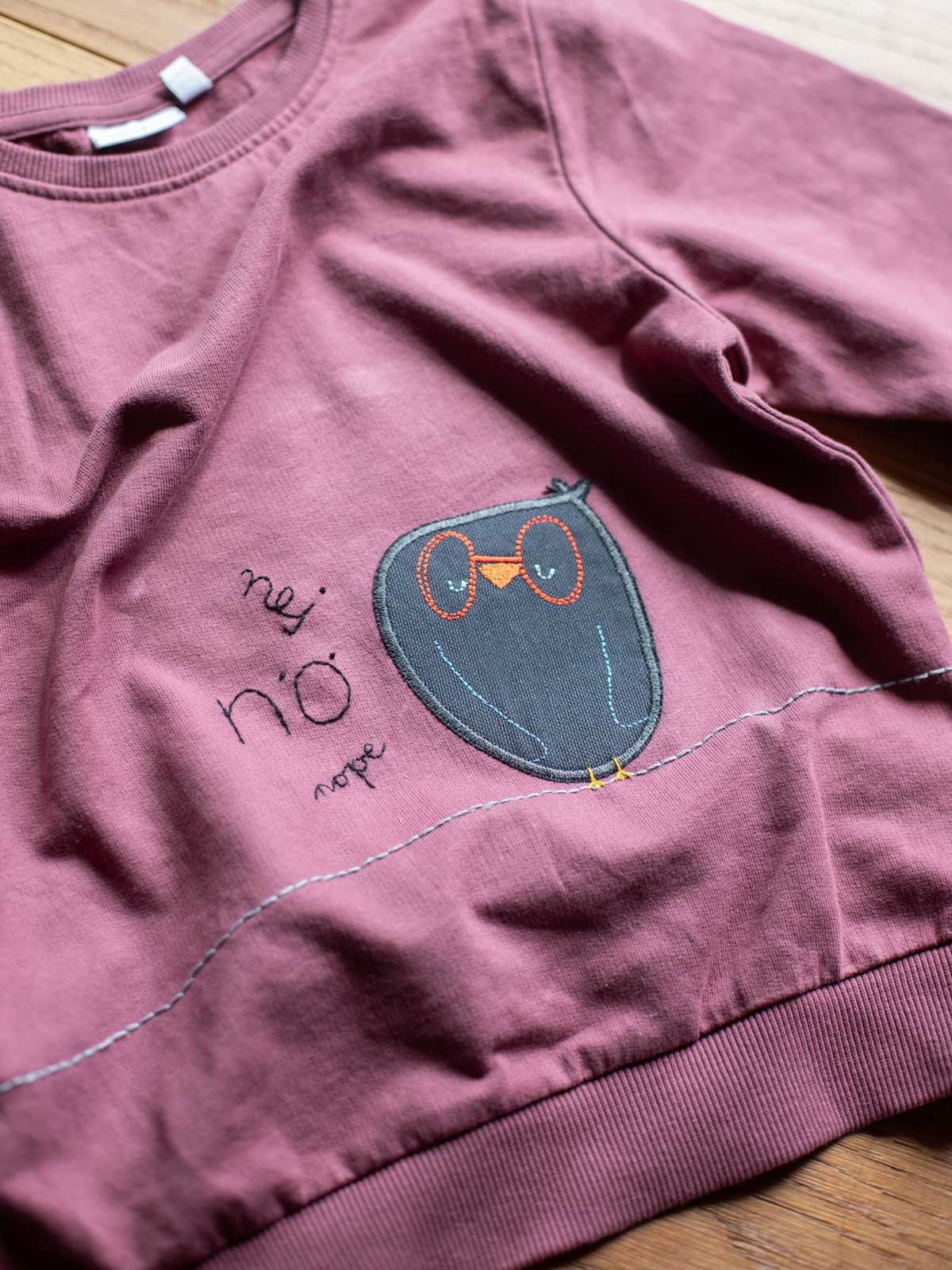 Knieflicken Eule auf einem lila Sweatshirt