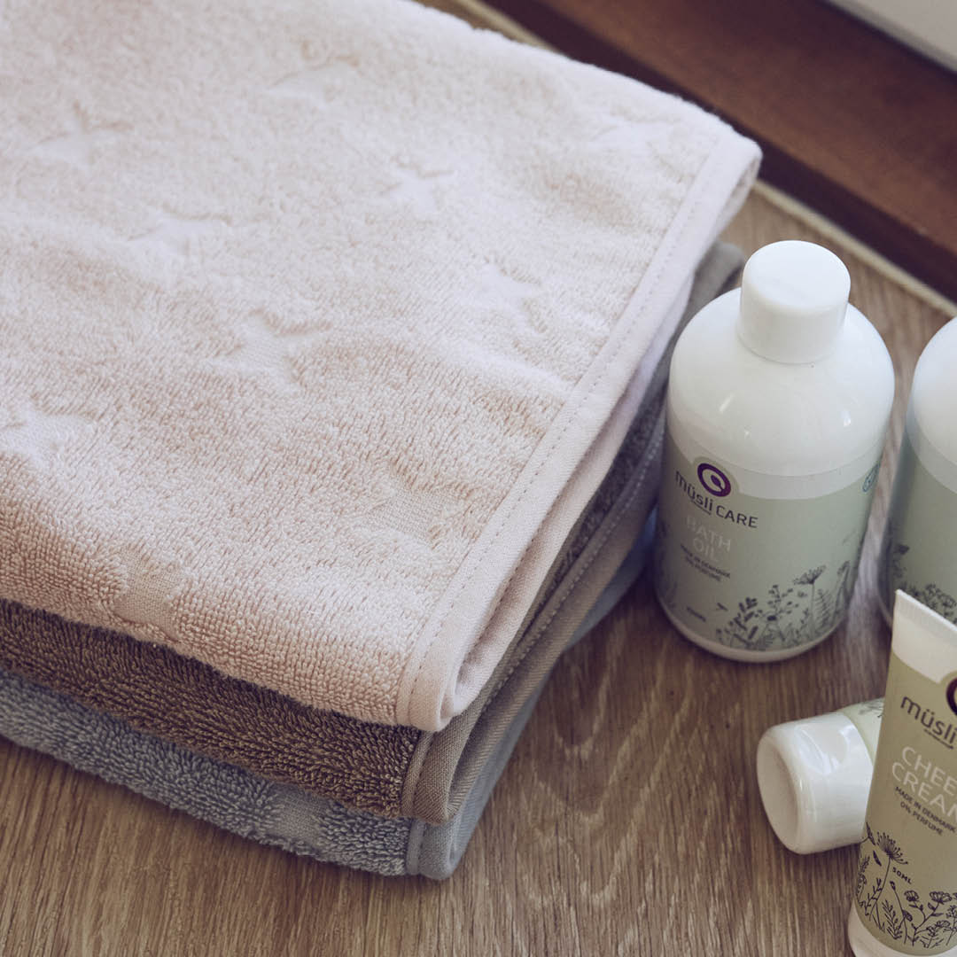 Stapel Handtücher auf einer Ablage mit einigen Fläschchen im Bad